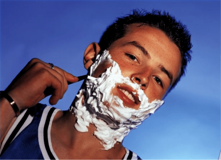 Adolescente afeitase e pensa na ampliación do pene